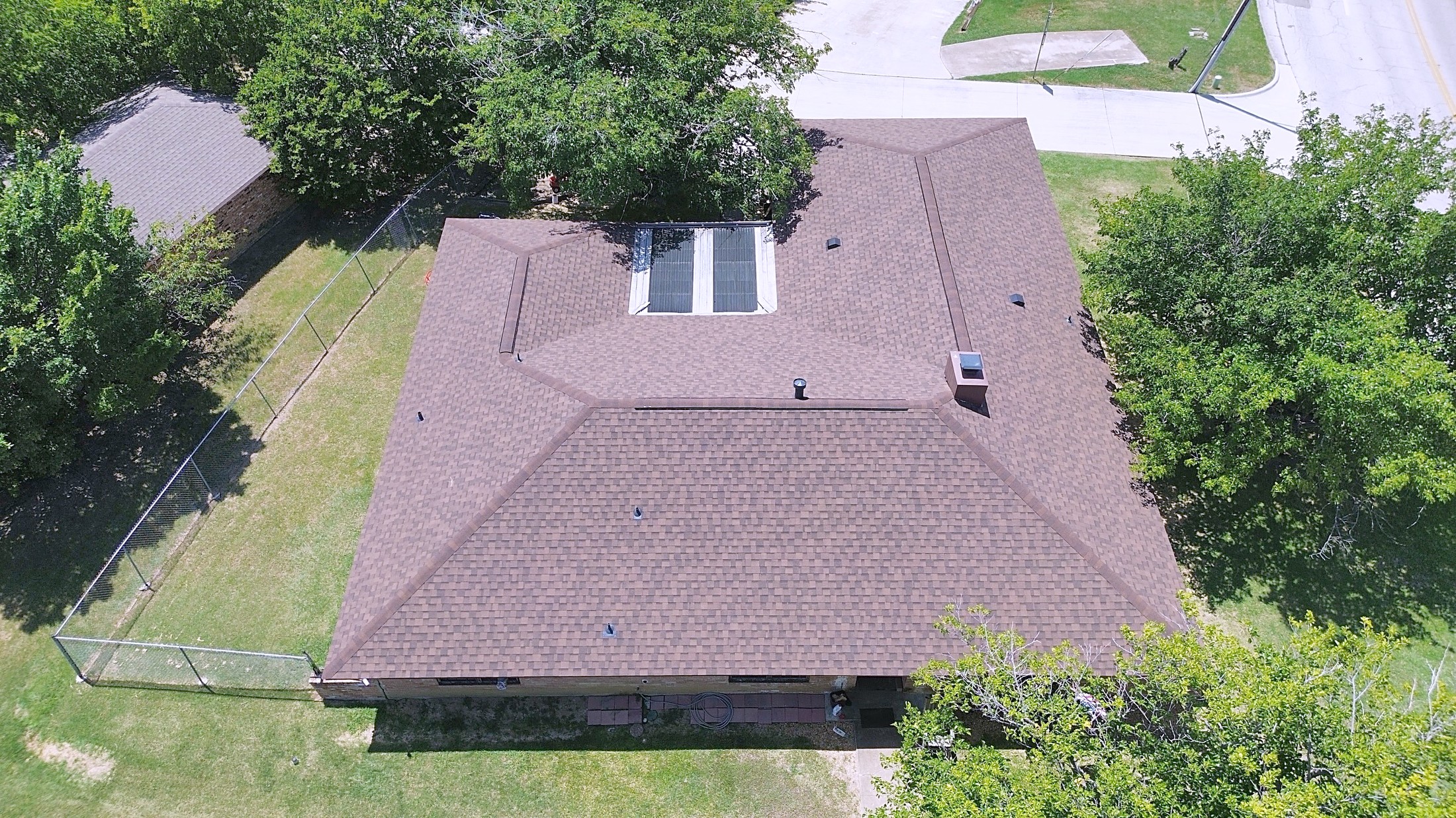 A finished charcoal shingle roof on a large single-story home, from the air