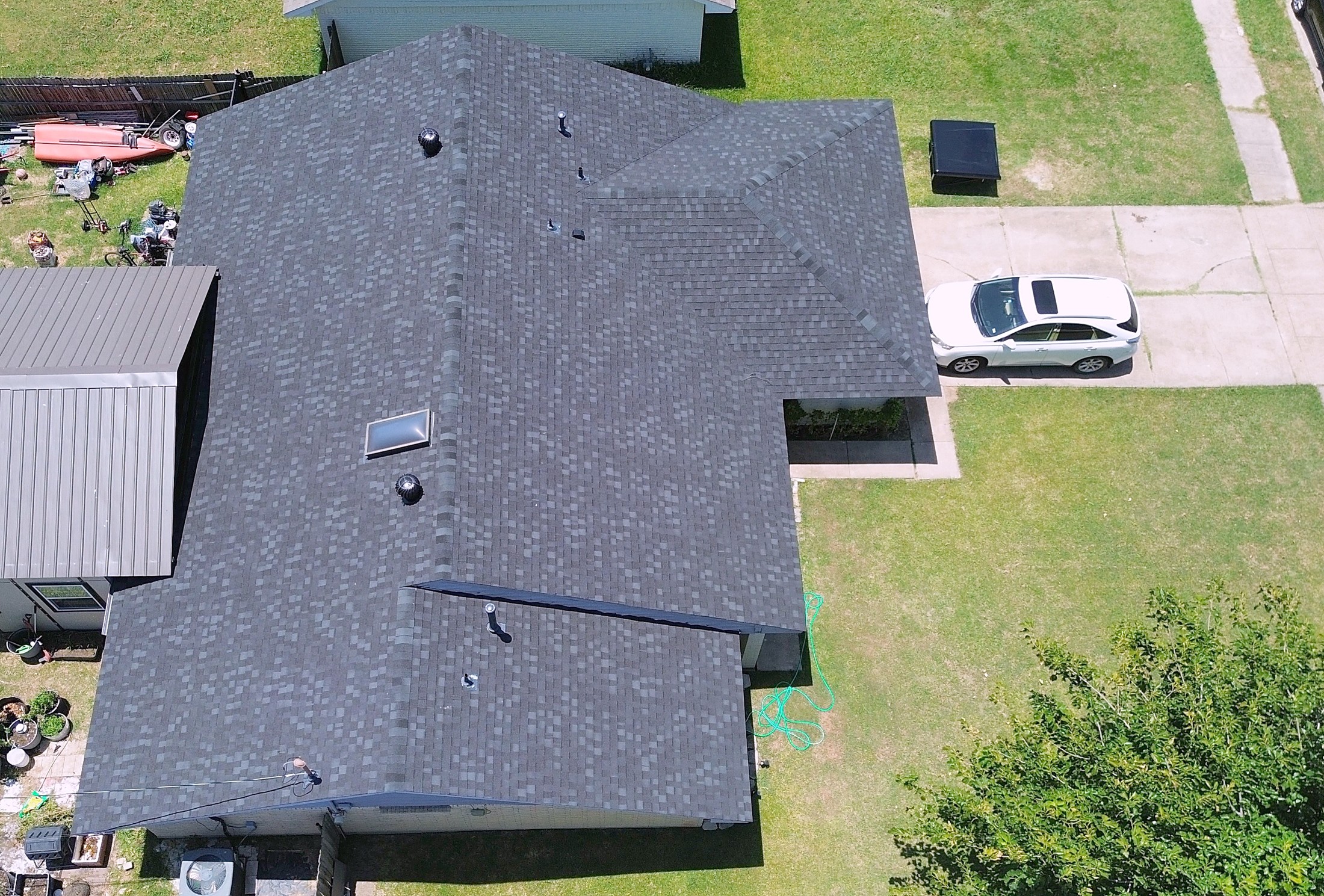 A finished charcoal shingle roof on a large single-story home, from the air