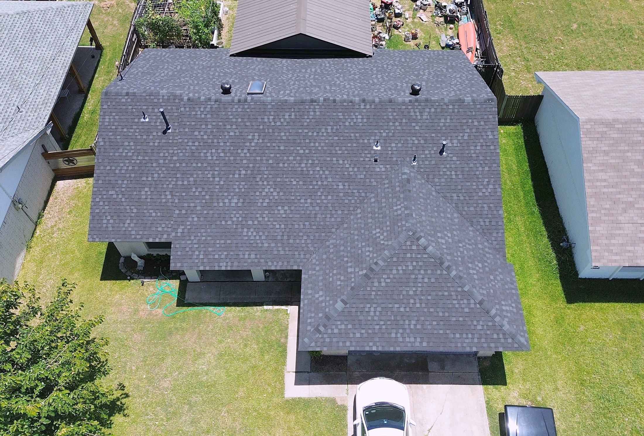 A finished charcoal shingle roof on a single-story brick home, photographed from directly above