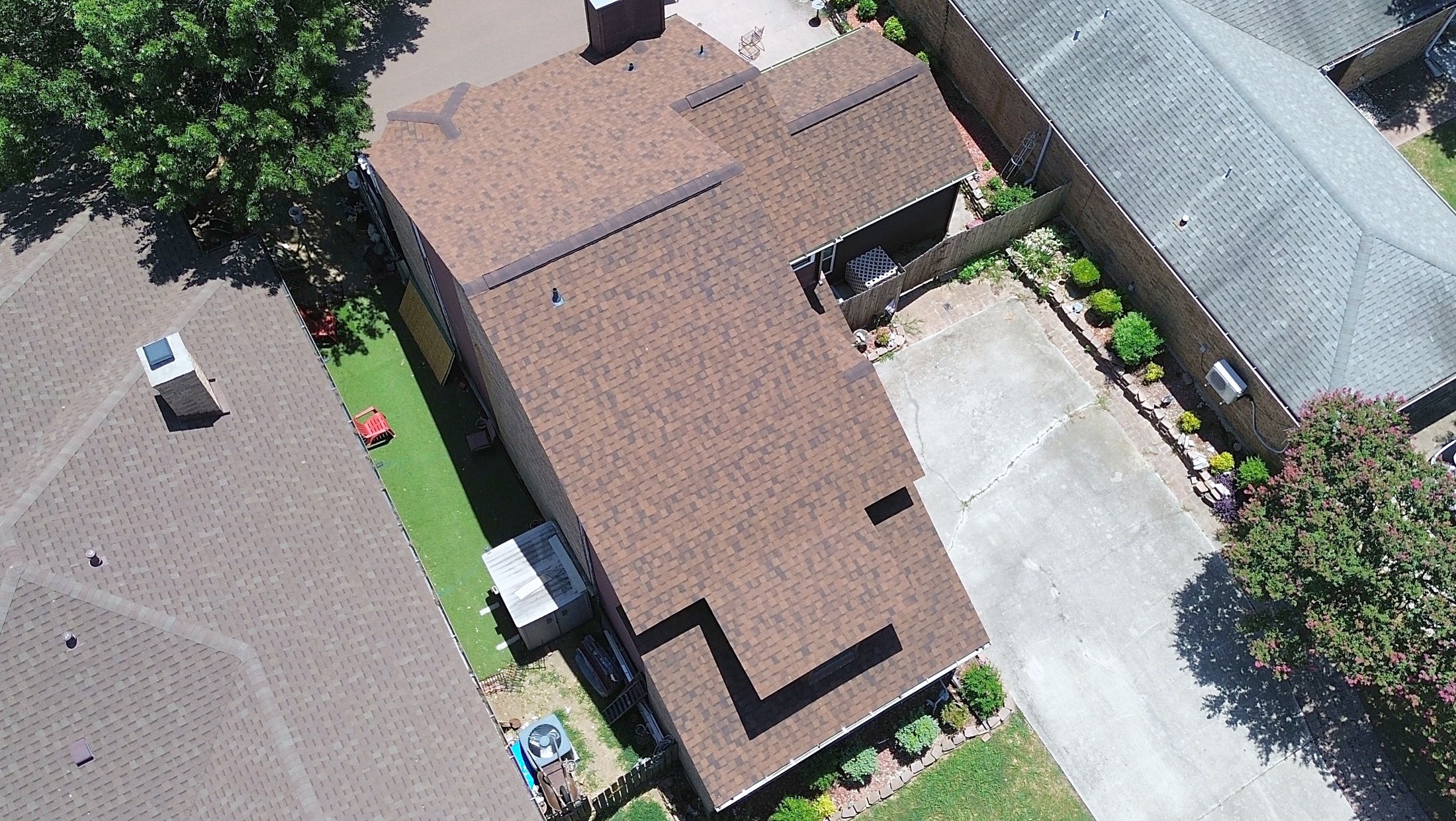 A wide charcoal shingle roof with a detached garage, from the air